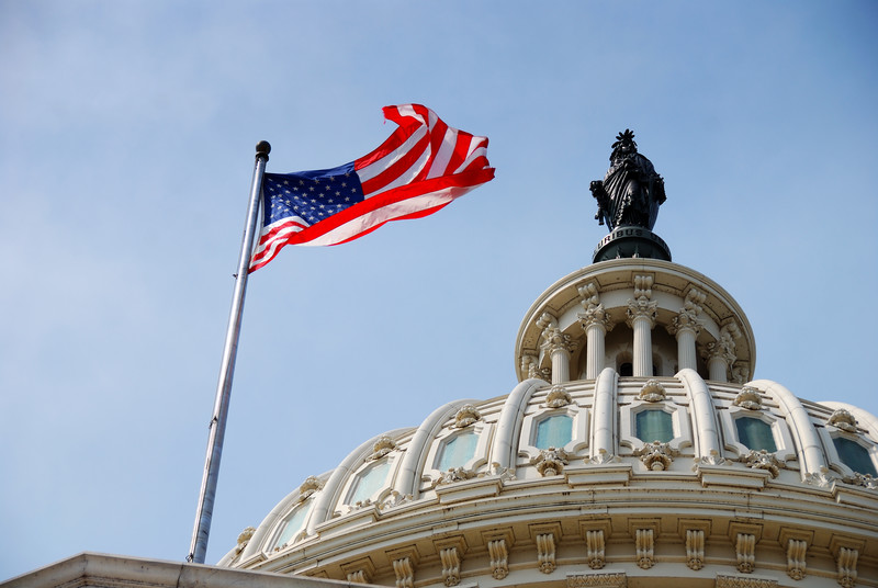 Artistic shot of the capitol dome and the American flag extended in the breeze.